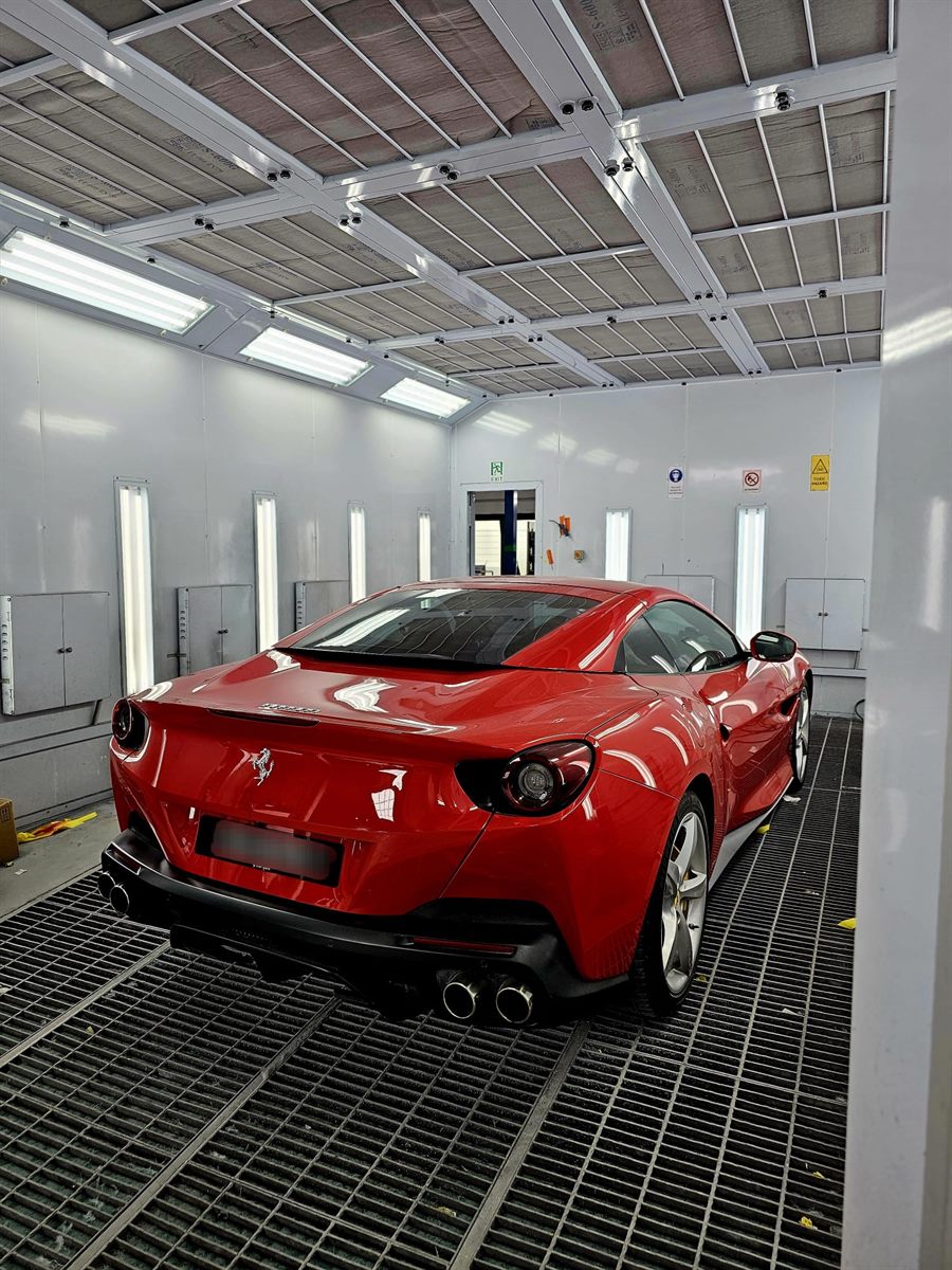 Red Ferrari inside a spray painting booth
