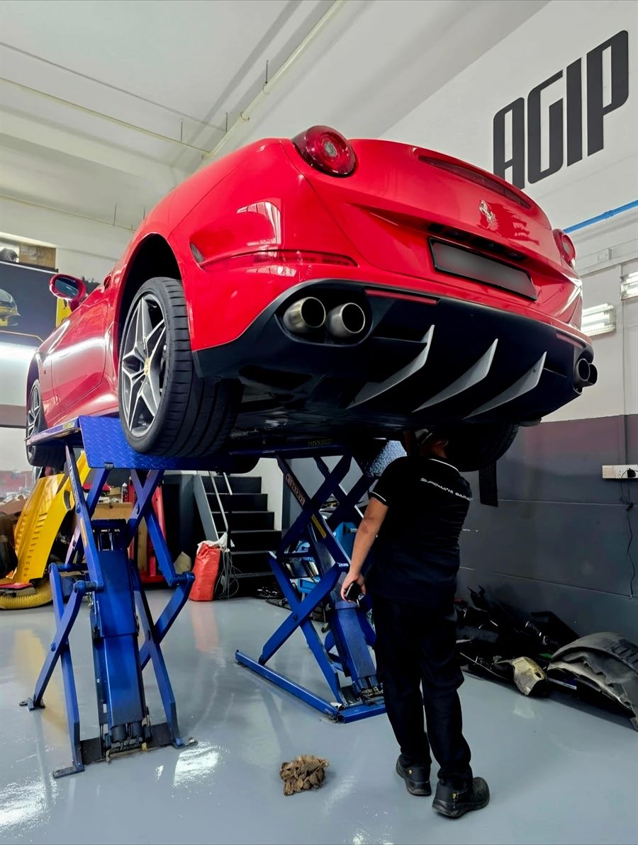 Red Ferrari raised on a workshop lift